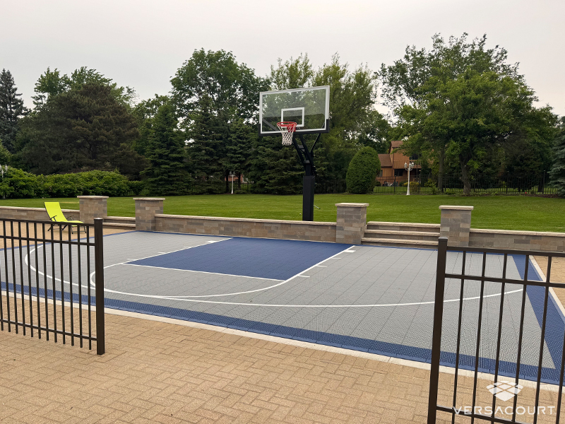 Ground-level backyard basketball court adjoining a paved patio, shown as VersaCourt design inspiration